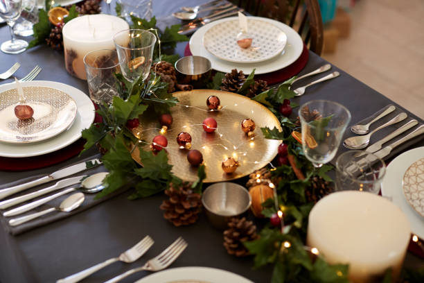 istock Christmas table setting with bauble name card holders arranged on plates, golden plate centrepiece with baubles, and green and red table decorations, elevated view 1056806360