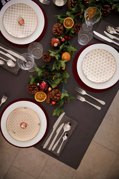 istock Christmas table setting with baubles arranged on plates and green and red table decorations, overhead view, vertical 1056806488
