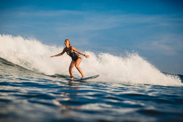 istock Young surfer woman with surfboard on wave. 1056825872