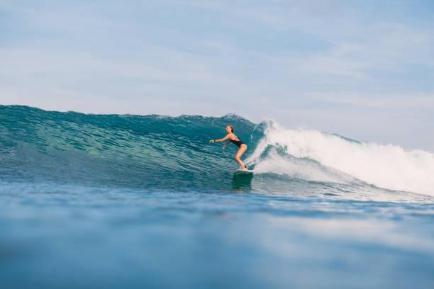 istock Young surfer girl at surfboard on overhead wave. 1056825984