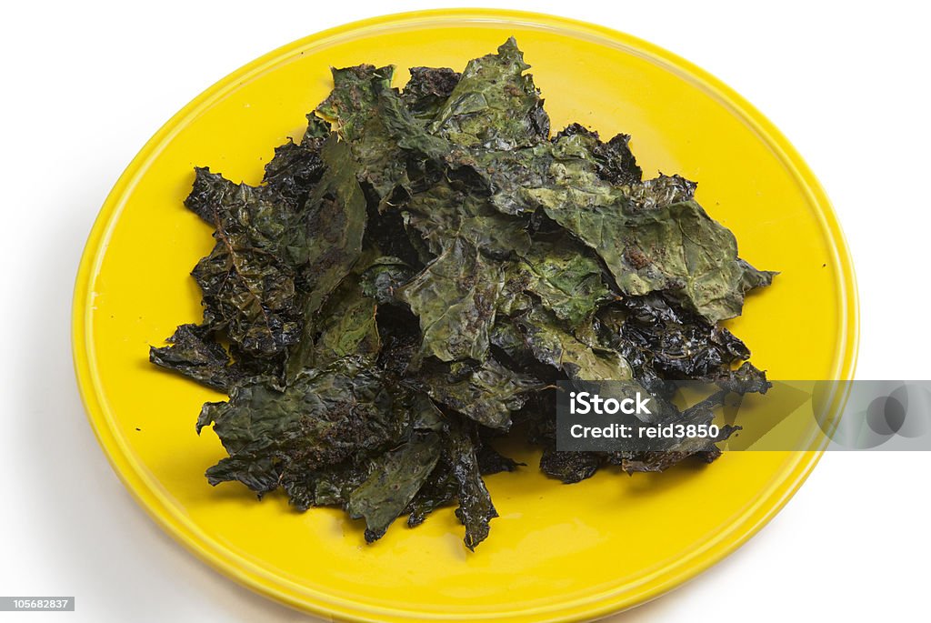 Kale Chips Homemade kale chips on yellow plate isolated on white background. Kale Stock Photo