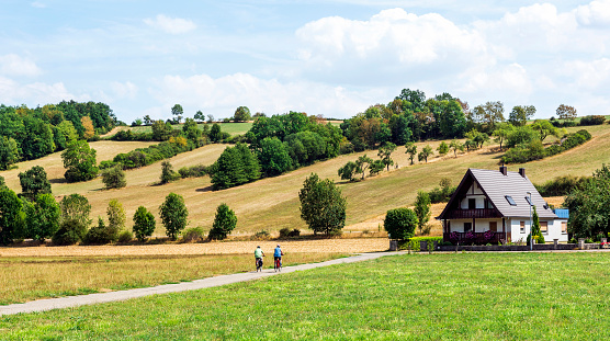 Farmhouse with two people on bicycles (Romantic Road - Romantische Strasse) at nature in Wurzburg, Germany.