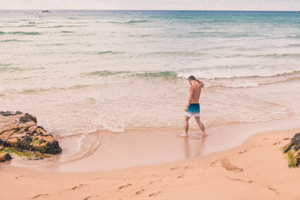 istock Man paddling at Pedn Vounder Beach, Cornwall on a June day. 1056829324