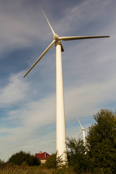 istock Windmill for electricity among the trees with the house. 1056835790