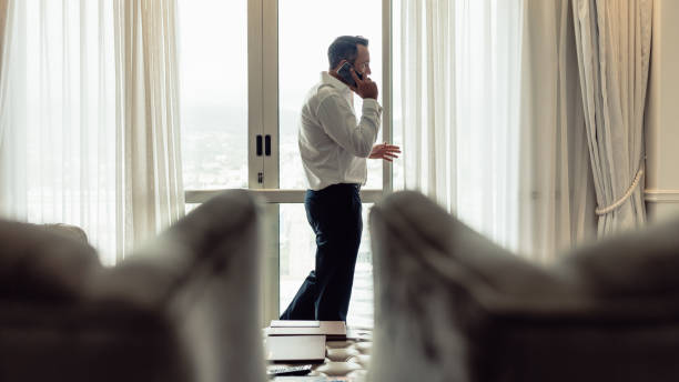istock Businessman talking over phone in hotel room 1056840578
