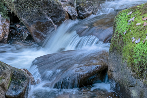 Waterfall on a UK Lakeland river with rocks covered in green moss