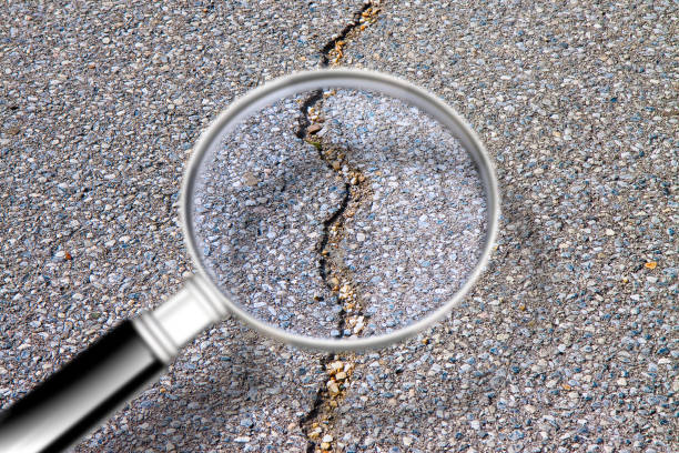 istock Cracked asphalt road damaged after a structural failure - Concept image seen through a magnifying glass
