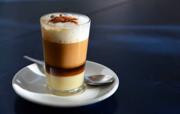 Traditional Canarian coffee Barraquito with separated layers of milk condensed and liquor on a dark background. stock photo