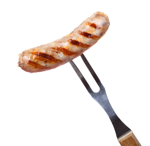 Grilled bratwurst on a fork against a white background Grilled bratwurst on a bbq fork isolated on white bratwurst stock pictures, royalty-free photos & images