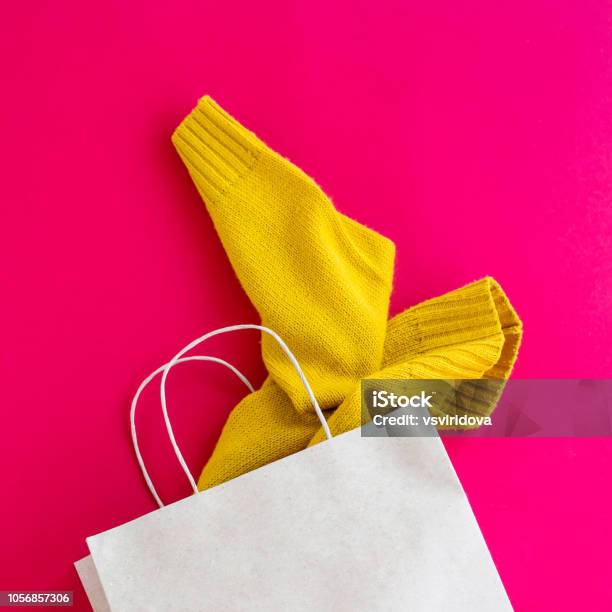 Paper Craft Package With Purchases Of Womens Clothing From Which The Yellow Sleeve Of The Sweater Sticks Out On A Bright Red Background Black Friday Concept Top View Flat Lay Stock Photo - Download Image Now