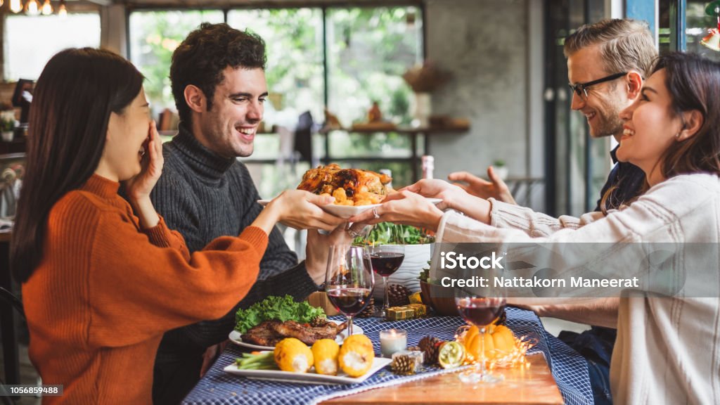 Group of young people celebrating Christmas party dinner with clinking glass of wine Thanksgiving - Holiday Stock Photo