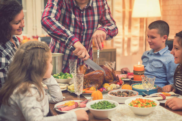 istock Young father carving roasted Thanksgiving turkey 1056864166
