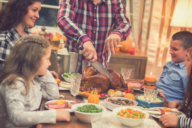 istock Young father carving roasted Thanksgiving turkey 1056864362