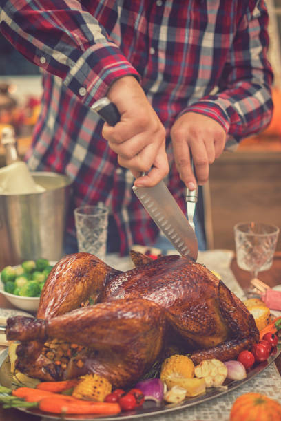 istock Young father carving roasted Thanksgiving turkey 1056864424