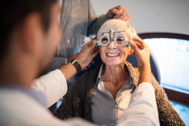 jeune ophtalmologue souriant vérifier l’acuité visuelle d’une vieille femme. - instrument optique photos et images de collection