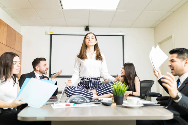 Easygoing Businesswoman Keeping Calm In Stressing Situation Young businesswoman meditating in lotus position while colleagues yelling during negotiation in office disagree funny stock pictures, royalty-free photos & images