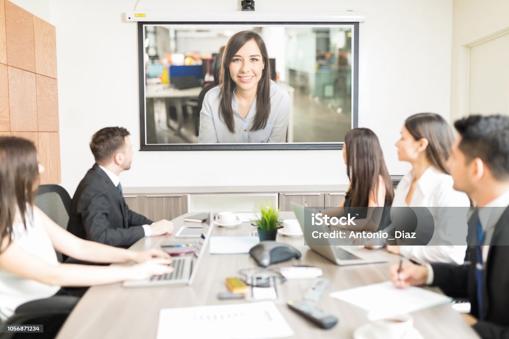 Executives Looking At Blank Projection Screen In Meeting Multiethnic male and female coworkers attending presentation in boardroom Video Conference Stock Photo