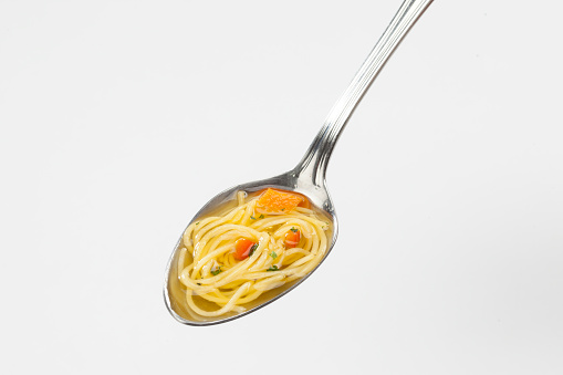 Spoon with noodle soup. Homemade style. Studio photography. High angle view.