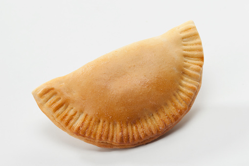 Empanada on white background. Studio shot. An empanada is a type of pasty baked or fried in many countries of the Americas and in Spain. Empanadas are made by folding dough over a stuffing, which may consist of meat, cheese or other ingredients.