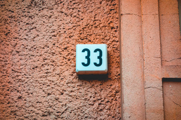 istock number 33 door sign on orange background facade 1056881790