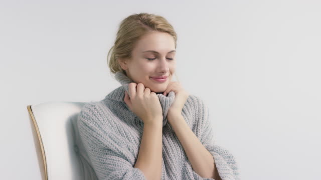 Smiling woman in sweater against white background