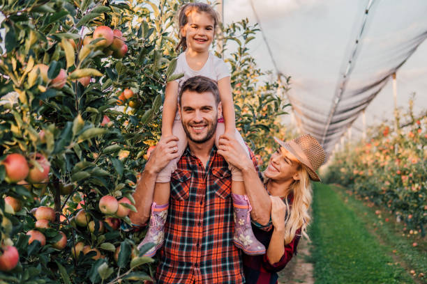 istock Parents with a child at apple orchard 1056886498