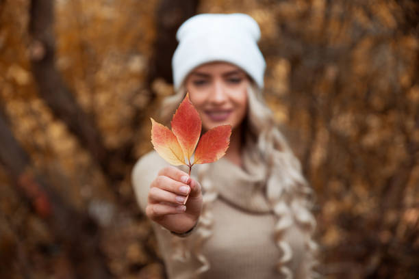 Young woman with cap holding leaf