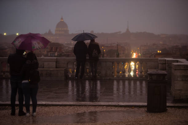 туристы с зонтиками во время дождливого дня в риме, наслаждаясь видом с пинсио на пьяцца-дель-пополо, с куполом святого петра далеко на гори� - cupola people rome lazio стоковые фото и изображения