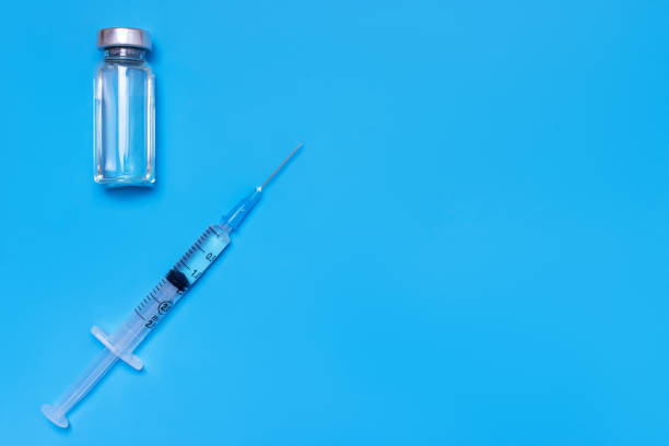 istock Syringe and vial on blue background with copy space, flat lay, top view 1056914028