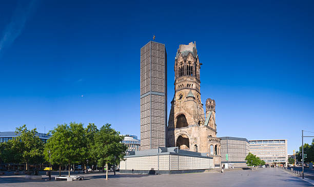 View of Kaiser-Wilhelmina-Gedachtnis-Kirche with blue skies One of Berlin's most famous landmarks, the Kaiser-Wilhelm-Gedächtnis-Kirche between the Europa-Center and Kurfürstendamm, the broken spire and modern bell tower overlook the busy Breitscheidplatz as symbols of the city's regeneration. Perspective corrected stitched panorama detailed when viewed large. kaiser wilhelm memorial church stock pictures, royalty-free photos & images