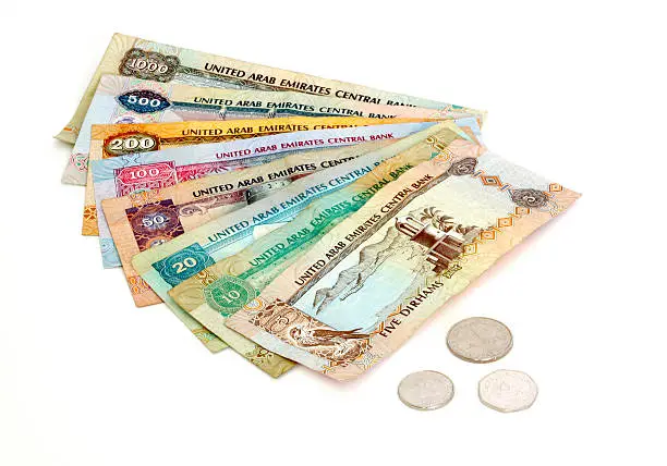 All denominations of United Arab Emirates Dirhams, notes and coins on white background. Notes and coins include: 1000 AED, 500 AED, 200 AED, 100 AED, 50 AED, 20 AED, 10 AED, 5 AED, 1 AED, 50 fils, 25 fils.