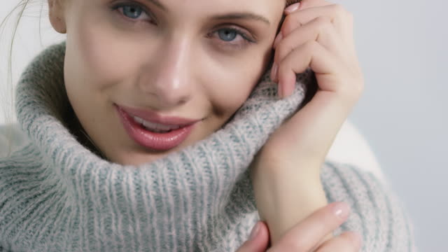 Beautiful woman covering face in soft sweater