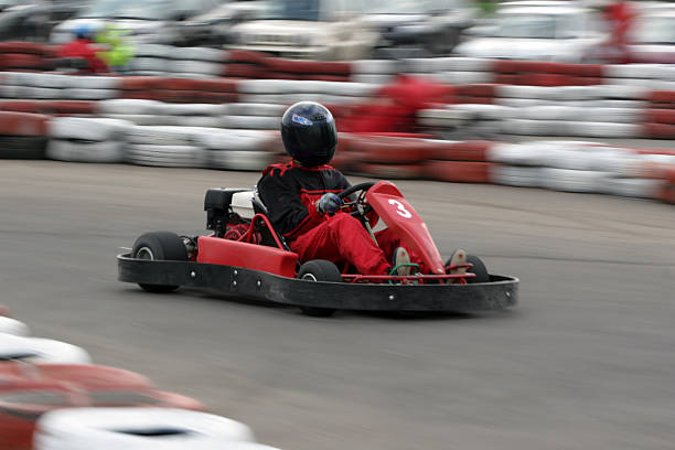 Individual in protective gear riding a go cart Go cart racer struggling on circuit  go carting stock pictures, royalty-free photos & images