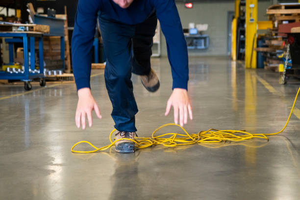 A worker tripping over an electrical cord in an industrial environment stock photo