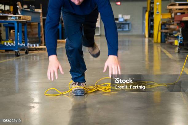 A Worker Tripping Over An Electrical Cord In An Industrial Environment Stock Photo - Download Image Now