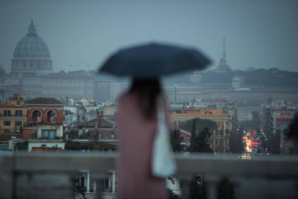 istock Rainy day in Rome: tourists with umbrellas 1056923930