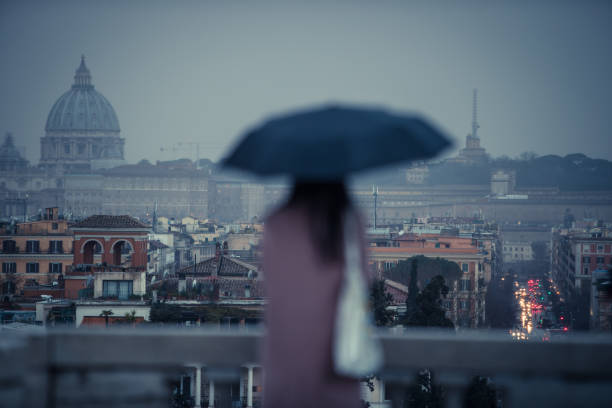 istock Rainy day in Rome: tourists with umbrellas 1056923946