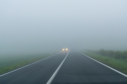 Foggy highway crossed by a bridge.\nRoad with poor visibility. Danger.