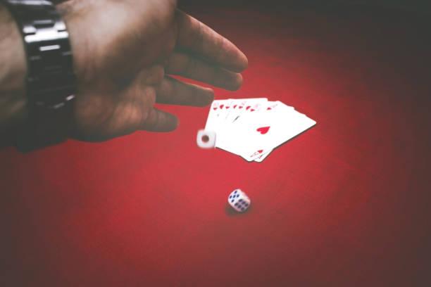 istock Male hand throwing dices on the red table with poker cards 1056926312