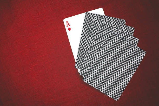 Close-up of a fan of playing cards, showing the corner of the Ace of Diamonds and the red-patterned backs.