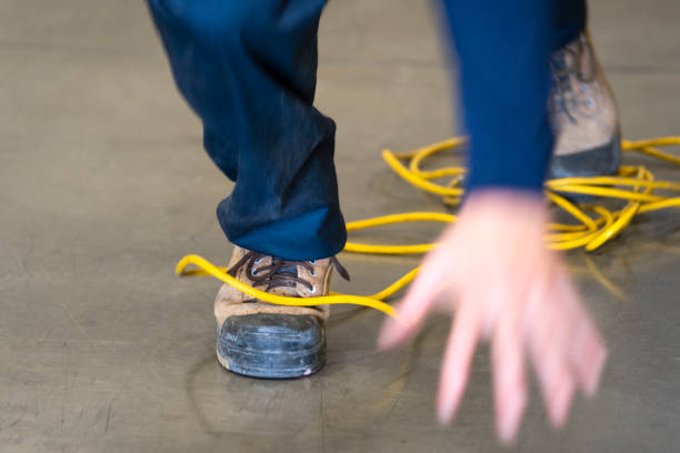 A worker tripping over an electrical cord in an industrial environment stock photo