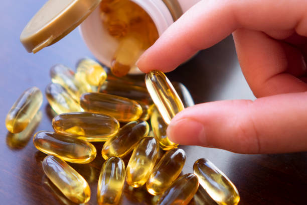 zdrowe odżywianie dietetyczne. kobieta trzymająca pigułkę z oleju rybnego w ręku. omega-3. witaminy i suplementy diety. wysoka rozdzielczość - fish oil vitamin pill cod liver oil nutritional supplement zdjęcia i obrazy z banku zdjęć