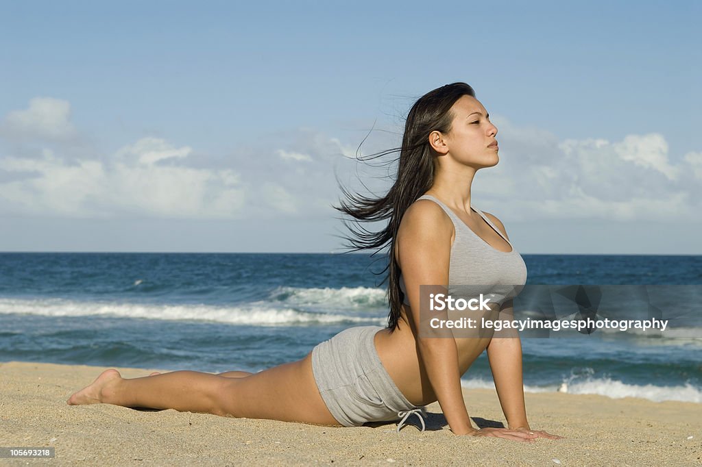 Young Woman Practicing Yoga Cobra Pose on the Beach Young woman practicing yoga on the beach.  She is practicing the Cobra Pose. Adult Stock Photo
