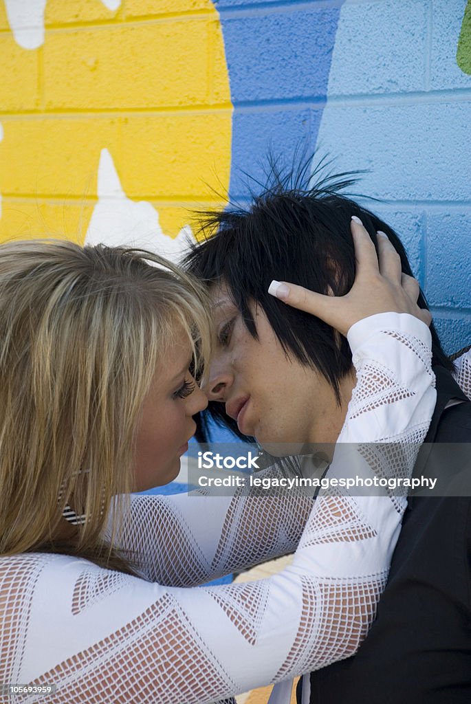 Young Couple Kissing in Front of a Grafitti Wall Young couple kissing in front of a grunge painted background. Adult Stock Photo