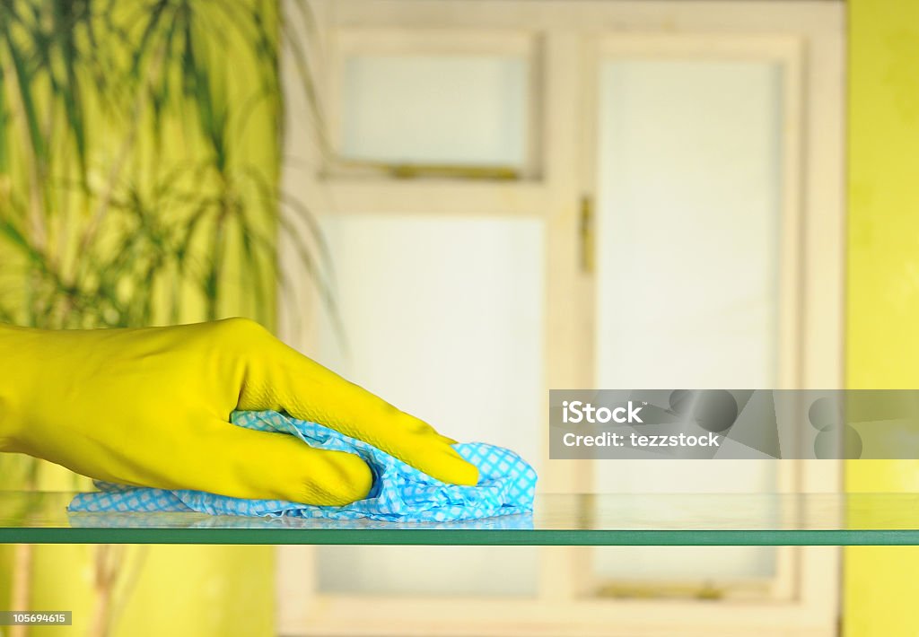Hand in yellow gloves doing spring cleaning person in rubber gloves using a blue duster Duster Stock Photo