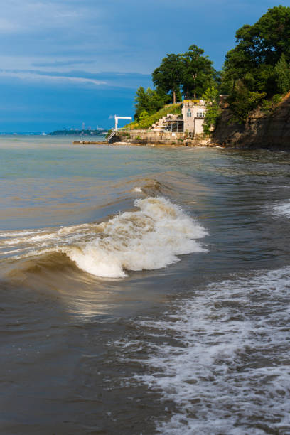 Waves crashing on the shore of Lake Erie with Cleveland skyline in the distance.