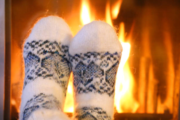 istock Feet in wool socks warming at the fireplace 1056954378