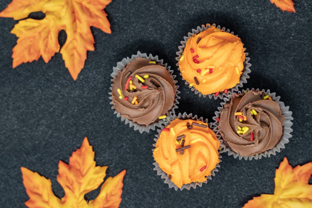 istock Maple leaves and Halloween cupcakes on black background 1056964296