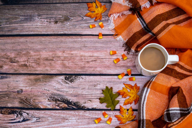 istock Cozy autumn coffee flat lay background with orange plaid blanket, candy corn, coffee cup and leaves. Wooden backdrop 1056966322