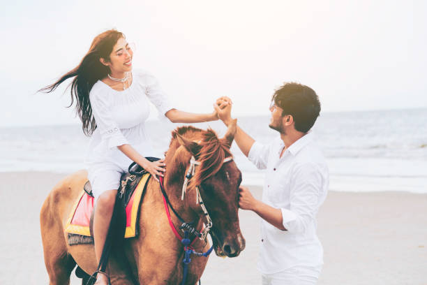 istock Young couple goes horse riding on tropical beach. 1056986310